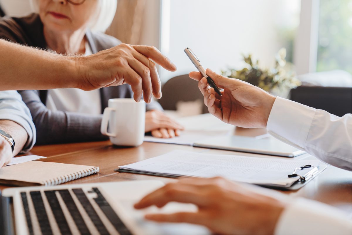 An older woman and a financial professional going through paperwork at a table